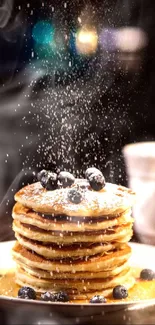 Stack of pancakes with blueberries and powdered sugar on top.