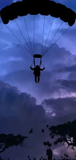 Silhouette of a parachuter against a purple sky with trees.