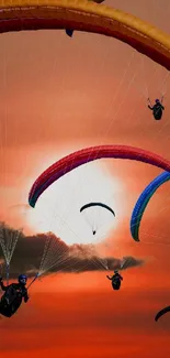 Colorful paragliders soar against a vibrant orange sunset sky.