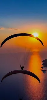 Paraglider silhouetted against a vibrant sunset over the ocean.