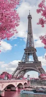 Eiffel Tower surrounded by pink blossoms and clear blue sky.