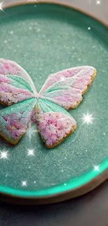 Pastel butterfly cookie design on teal plate.