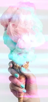 Hand holding pastel pink and blue cotton candy in a cone.