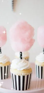 Pastel pink cupcakes with cotton candy topping on a stand.