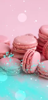 Pastel pink macarons with turquoise powder on a pink background.