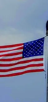 American flag with eagle perched on flagpole under blue sky.