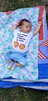 Sleeping baby on colorful outdoor blanket.