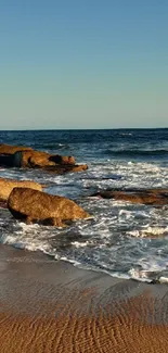 Peaceful beach sunset with waves and rocks.