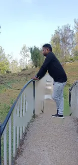 Man standing on a bridge surrounded by nature.