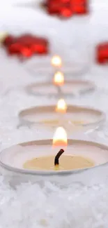 Candlelight on snow with red decorations creating a peaceful ambiance.