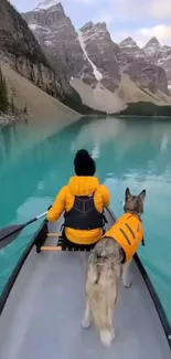 Person and dog canoeing on a serene turquoise lake beneath snowy mountains.