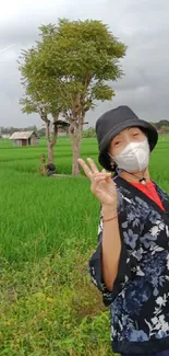 Woman enjoying a serene countryside with green fields and a distant tree.