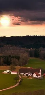 Countryside sunset view with dark green fields and dramatic evening sky.