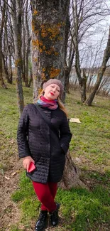 Woman relaxing against a tree in a peaceful forest setting.