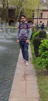 Man standing in a serene garden next to a reflective fountain pond.