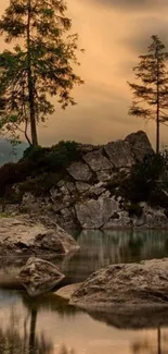 Sunset over a tranquil lake with rocky terrain and trees reflecting in the water.