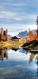 Reflection of a cottage by a lake with autumn trees.