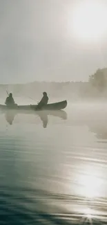 Two canoers on a misty lake at sunrise.