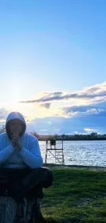 Meditative figure at serene lakeside during sunset.