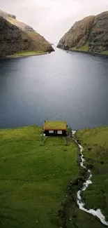 Scenic wallpaper with a cabin by a lake and lush green hills.