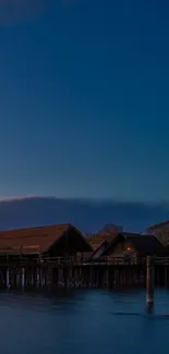 Tranquil evening scene with huts over a dark blue lake.