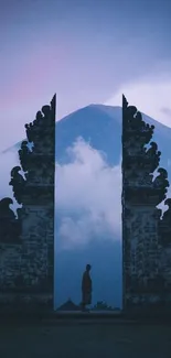 Mystical gateway framing mountain under misty, cloud-covered sky.