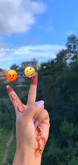 Henna hand gesture with emojis against nature background.