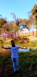 Person enjoying nature by a serene pond with trees and clear blue sky.