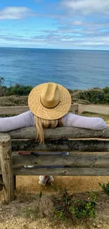 Woman relaxes on bench overlooking ocean with blue sky and clouds.