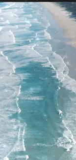 Aerial view of calming ocean waves meeting sandy beach.