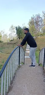 Person standing on a bridge in a serene park.