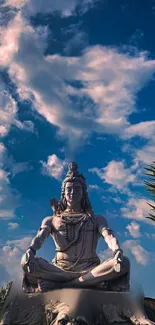 Shiva statue with a blue sky background in meditation.