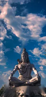 Serene Shiva statue surrounded by a vivid blue sky and fluffy clouds.