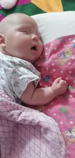 Adorable baby peacefully sleeping on pink blanket.