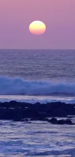 Purple sunset over a tranquil ocean with gentle waves and a calm beach.