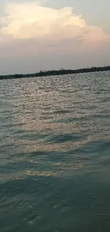 Sunset over a calm lake with rippling water and serene blue sky.