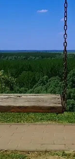 Wooden swing with a scenic forest view under blue sky.