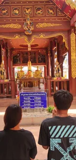 Two people meditating at a tranquil temple setting with ornate decor.