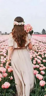 Woman walking through pink tulip field with flowers in hand.