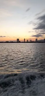 Serene cityscape at sunset with calm waters and skyline silhouette.