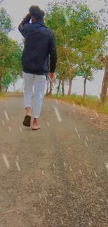 Man walking on a forest path with lush trees in a serene setting.