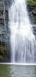 Serene waterfall cascading over rocks with lush green surroundings.