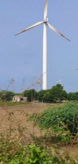 Wind turbine in a sunny, green landscape with blue sky.