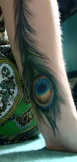 Vibrant peacock feather tattoo on a leg with green paisley background.