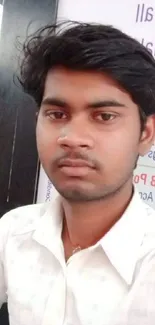 Portrait of a young man in a casual white shirt, posing thoughtfully.