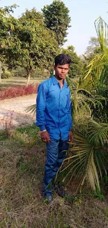 A person in blue attire surrounded by lush greenery in a serene outdoor setting.