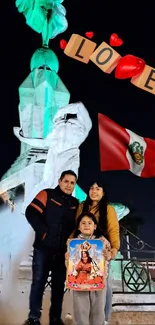 Peruvian monument with love symbols and family under night sky backdrop.