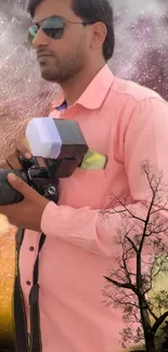 Photographer in pink shirt with artistic background and silhouette of a tree.