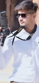 Young stylish photographer holding camera outdoors.