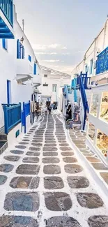 Picturesque Greek village street with white buildings and blue accents.